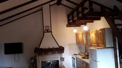 a kitchen with a fireplace and a television and a kitchen with at Weekend House Petar in Lusnić