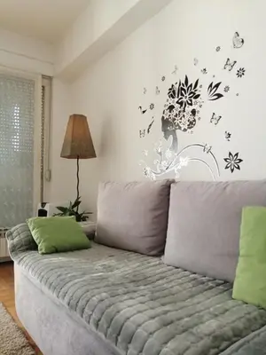a living room with a couch with flowers and birds on the wall at Apt Ana in Banja Luka