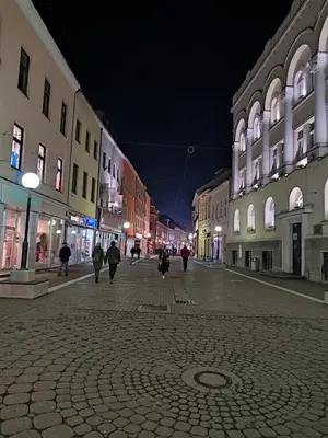 a city street at night with people walking down the street at Apt Ana in Banja Luka