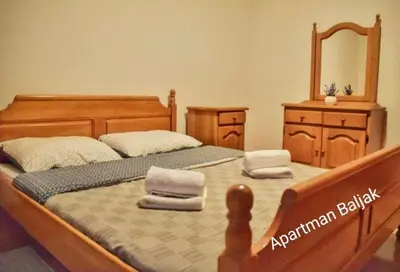 a bedroom with a wooden bed and a mirror at Apartman Baljak in Livno