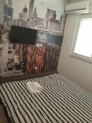 a bed in a room with a poster of a city at SOBE ROOMS GAVRILO in Banja Luka