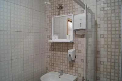 a white tiled bathroom with a sink and a mirror at SOBE ROOMS GAVRILO in Banja Luka