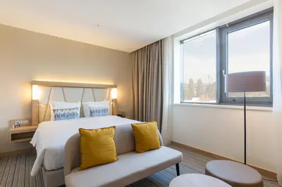 a hotel room with a bed with yellow pillows at Courtyard by Marriott Banja Luka in Banja Luka