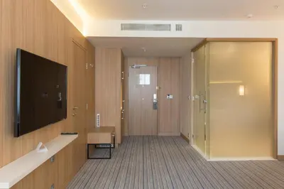 a bathroom with a television and a walk in shower at Courtyard by Marriott Banja Luka in Banja Luka
