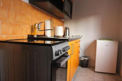a kitchen with a black stove and a refrigerator at Apartmani Ramonda in Teslić