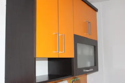 a kitchen with orange and black cabinets and a microwave at Apartmani Ramonda in Teslić