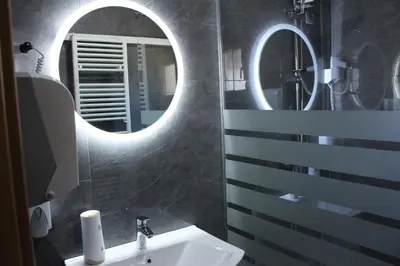 a bathroom with a sink and two mirrors at Apartmani Ramonda in Teslić