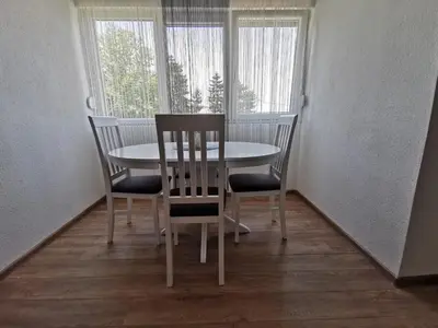a table and chairs in a room with windows at Apartman MMS in Teslić
