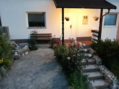 a house with a porch with a bench and flowers at Apartment AMRA in Tuzla