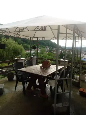 a wooden table and chairs under an umbrella at Apartment AMRA in Tuzla