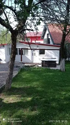 a white building with a bench in the grass at Ravne Apartman in Visoko