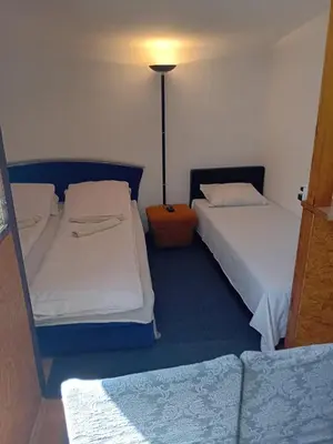 two beds in a room with a lamp and a couch at Ravne Apartman in Visoko
