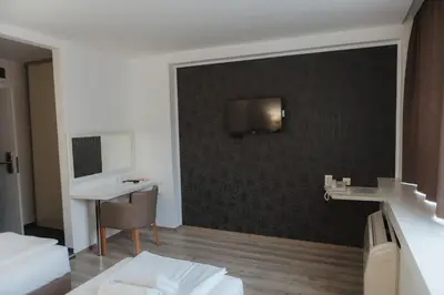 a hotel room with a bed and a desk and a wall at Hotel Slavija Banja Luka in Banja Luka