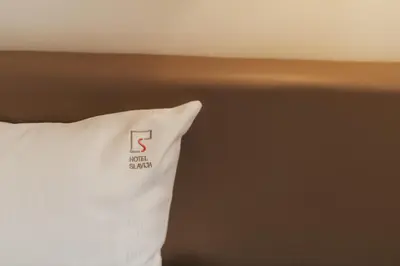 a white pillow with the letter s on it at Hotel Slavija Banja Luka in Banja Luka