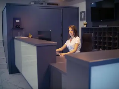 a woman sitting at a desk with a laptop at Hotel Slavija Banja Luka in Banja Luka