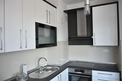 a kitchen with white cabinets and a sink and a microwave at Relax Teslić in Teslić