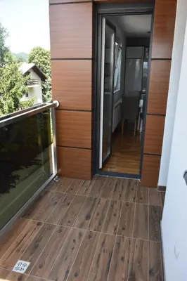 a balcony with wooden flooring and sliding glass doors at Relax Teslić in Teslić
