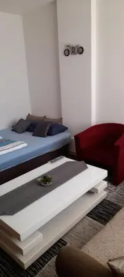 a bedroom with a bed and a red chair at Irma in Tuzla