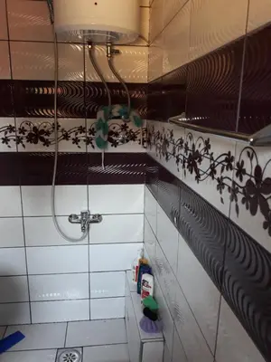 a bathroom with a shower with black and white tiles at City Apartment in Visoko