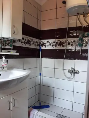 a shower in a bathroom with black and white tiles at City Apartment in Visoko