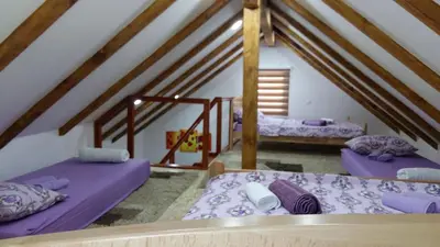 two beds in a attic room with wooden beams at Villa Queen in Visoko