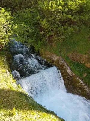 a small waterfall on a hill with grass and trees at Panorama Travnik in Travnik