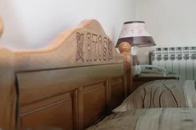 a bed with a wooden head board next to a lamp at Motel Atos in Laktaši