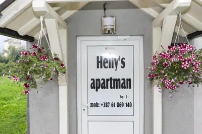 a sign on a house with flowers in front of it at Helly's apartman - self check-in - in Jajce