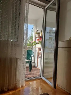 a sliding glass door leading to a balcony with a green chair at Stan na dan 