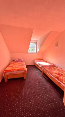 an attic room with two beds and a window at Apartman Torlakovac in Donji Vakuf