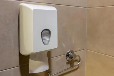 a white soap dispenser on a wall in a bathroom at Hotel IUT in Travnik