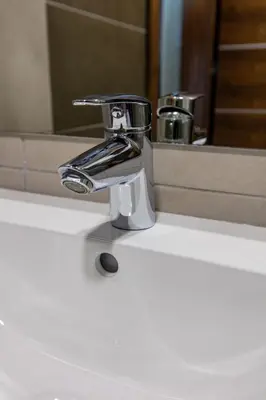 a chrome bathroom sink faucet in front of a mirror at Hotel IUT in Travnik