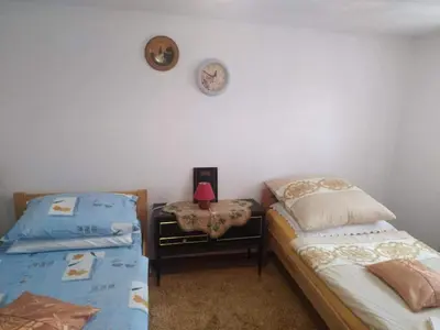a bedroom with two beds and a clock on the wall at Apartman Ana in Livno