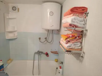 a bathroom with a bath tub and towels on a shelf at Apartman Ana in Livno