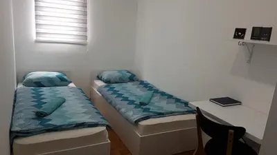 two beds in a room with a desk and a window at Apartment Emina in Travnik