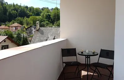 a balcony with two chairs and a table with a view at Apartment Emina in Travnik