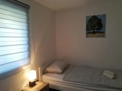 a bedroom with a bed with a tree picture on the wall at Kuća Vila Nina in Tomislavgrad