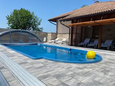 a swimming pool with a yellow ball next to a house at Vikendica Atos in Nova Topola