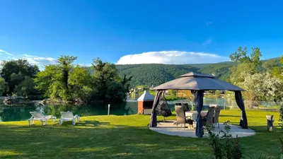 a gazebo with chairs and tables next to a lake at Apartman Deluxe Una Holiday in Bihać