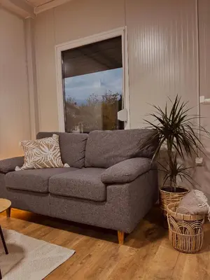 a gray couch in a living room with a plant at Apartman Deluxe Una Holiday in Bihać