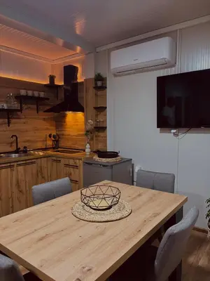 a kitchen with a wooden table with chairs and a television at Apartman Deluxe Una Holiday in Bihać