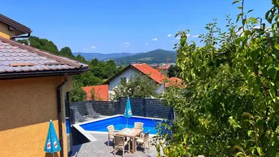 a swimming pool with a table and chairs next to a house at Villa Sun Visoko in Visoko
