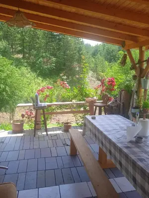 a patio with a wooden table and a bench at Spacious and Charming House in Vozuća with Large Garden in Vozuća