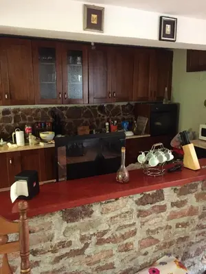 a kitchen with wooden cabinets and a counter with pots and pans at Spacious and Charming House in Vozuća with Large Garden in Vozuća