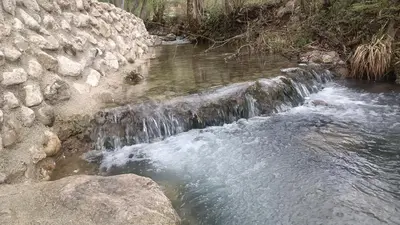a small waterfall on a river next to a stone wall at Live Nature in Bihać