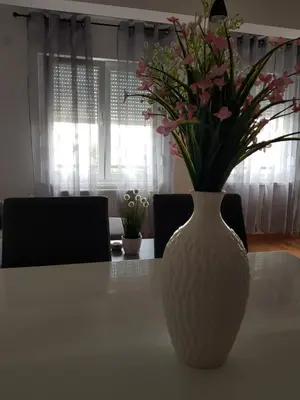 a white vase with flowers sitting on a table at Apartman DIJANA in Banja Luka