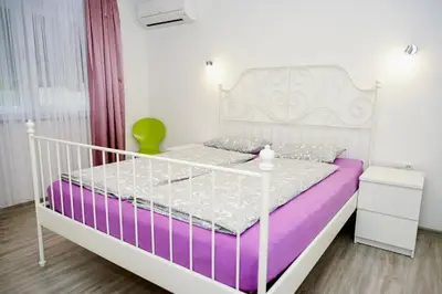 a white bedroom with a white bed and a green chair at Villa Jajce in Jajce