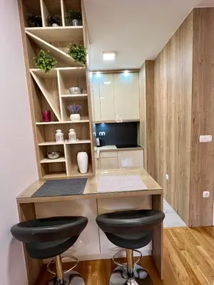 a kitchen with a desk and two stools in a room at Apartman Lux Doboj 2 in Doboj