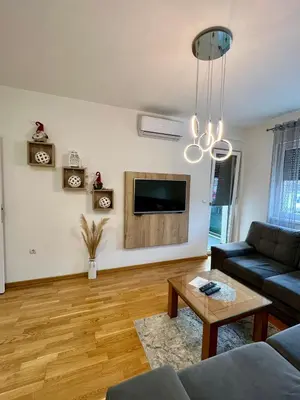 a living room with a couch and a tv on a wall at Apartman Lux Doboj 2 in Doboj