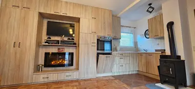 a kitchen with wooden cabinets and a fireplace at Vikendica Kod Koje in Banja Luka